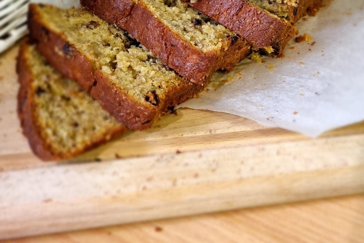 Thick slices of moist homemade banana bread on parchment paper on a wooden board