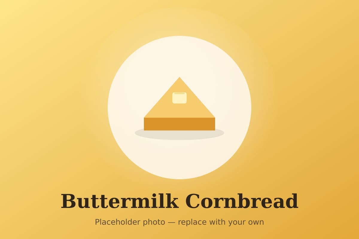 Golden buttermilk cornbread in a cast-iron skillet with one wedge removed, showing a tender yellow crumb