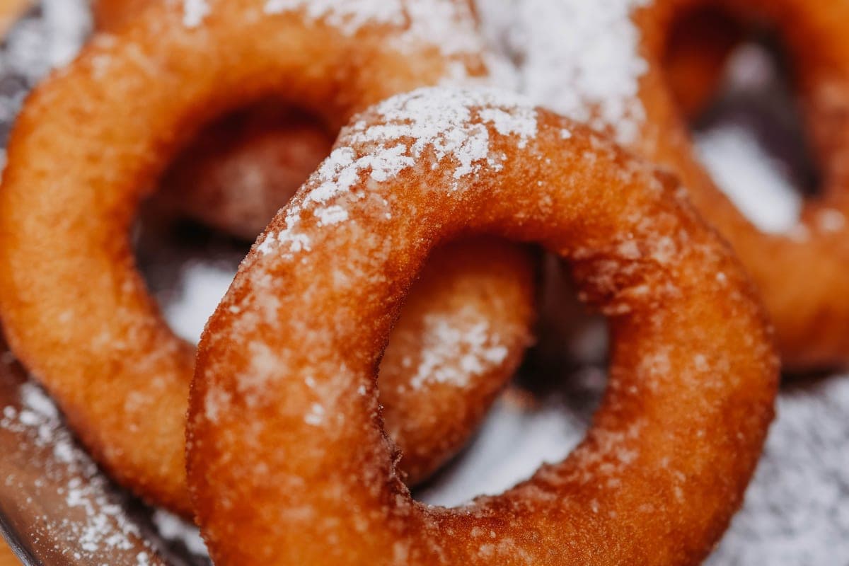 Golden old-fashioned cake donuts dusted with powdered sugar, piled on a plate