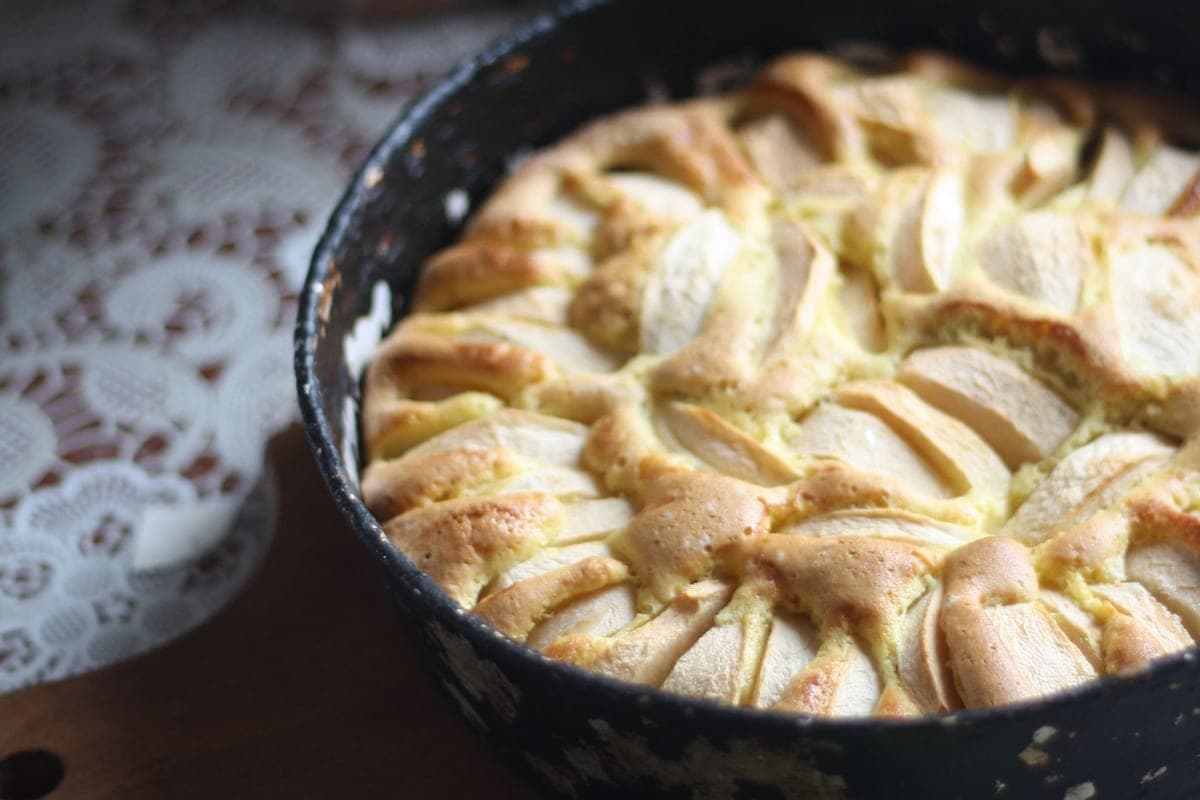 A rustic apple pie baked in a black cast-iron skillet, its top covered in rings of golden baked apple slices